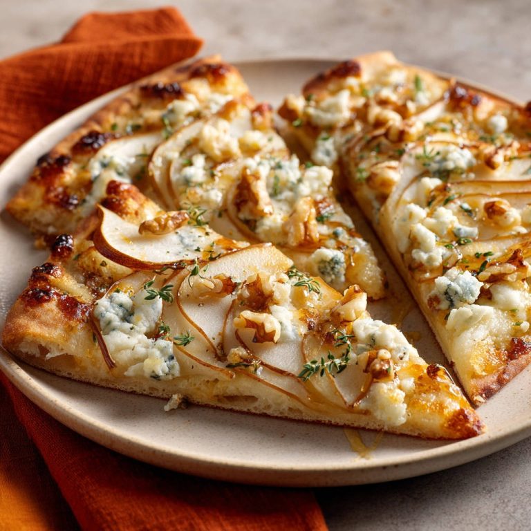 Birnen-Blauschimmelkäse Pizza, angeschnitten und von nah aufgenommen, zeigt saftige Birnenscheiben und zerbröselten Käse.
