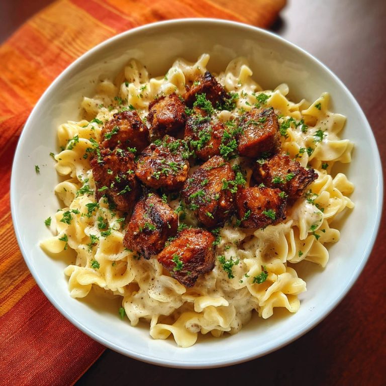 Pasta mit cremiger Sauce und Hähnchen, eine Nahaufnahme des Gerichts mit gebratenen Hähnchenstücken und Petersilie garniert.
