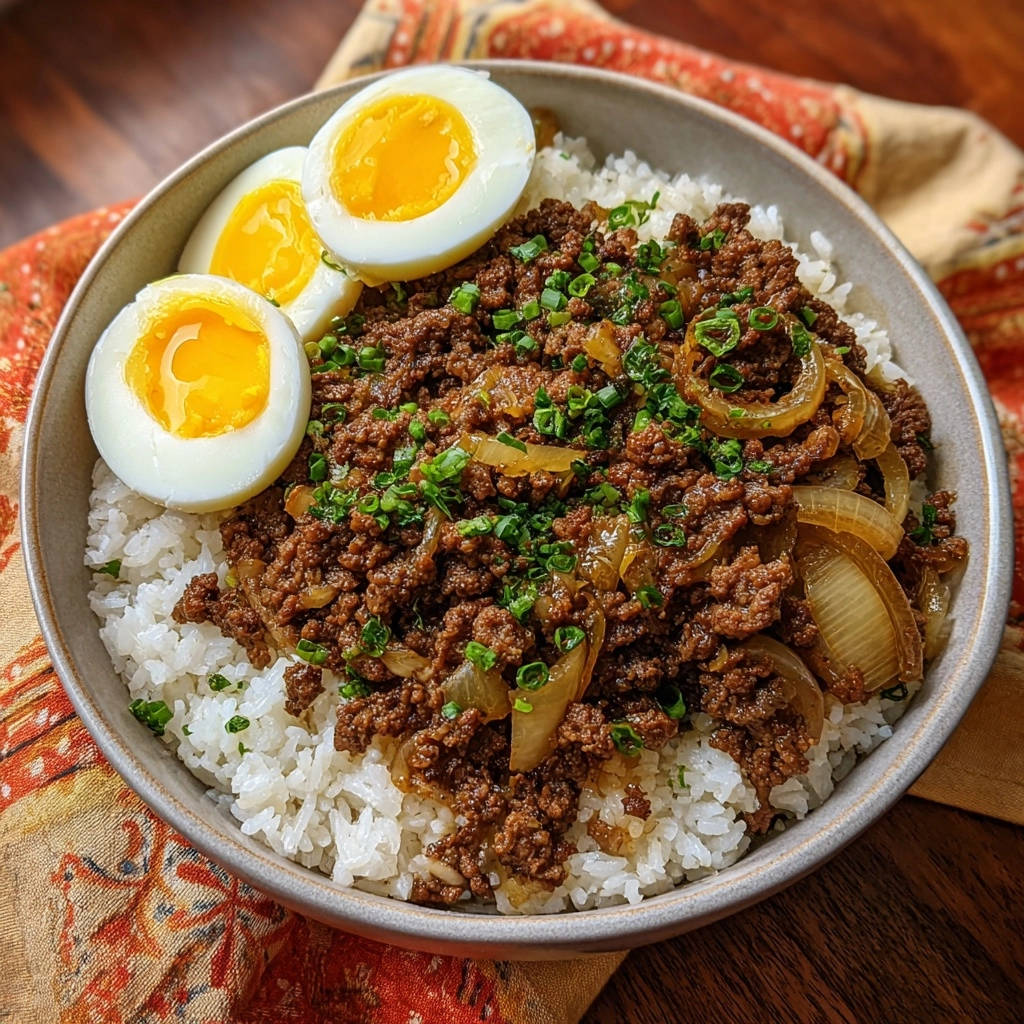 Asiatische Hackfleisch-Reis-Bowl mit einem hartgekochten Ei, serviert in einer Schüssel auf einem gemusterten Tuch.