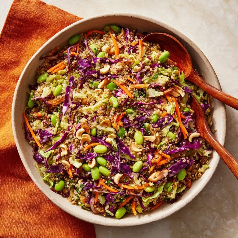 Knackiger Quinoa-Krautsalat mit Edamame und Cashews, serviert in einer Schale mit Holzkochlöffeln, von oben gesehen.
