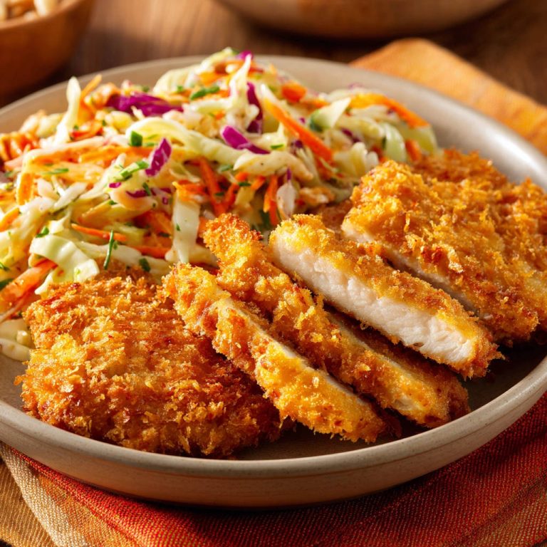Knuspriges Hähnchen mit Coleslaw, angeschnitten und auf einem Teller mit Salat serviert