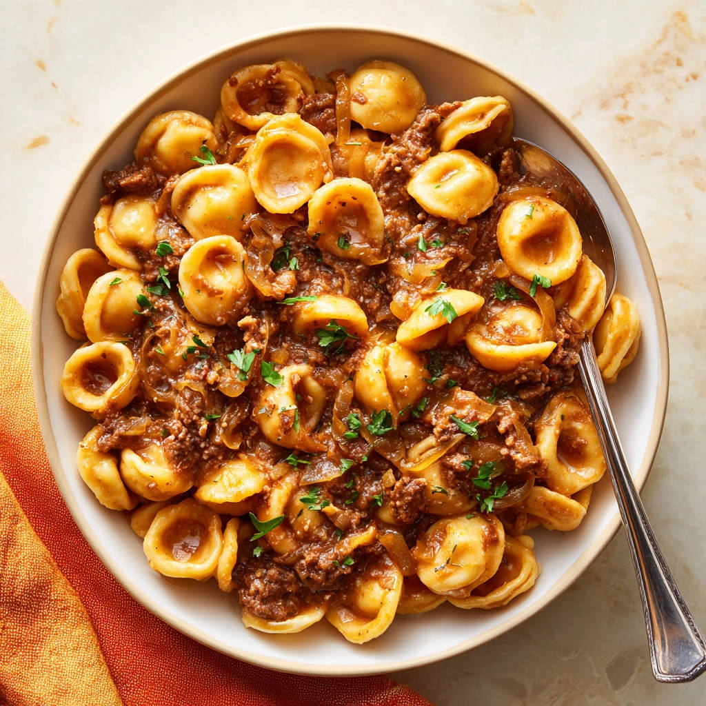 Orecchiette mit Hackfleischsoße in einer Schüssel, Nahaufnahme mit Löffel und Petersilie garniert.
