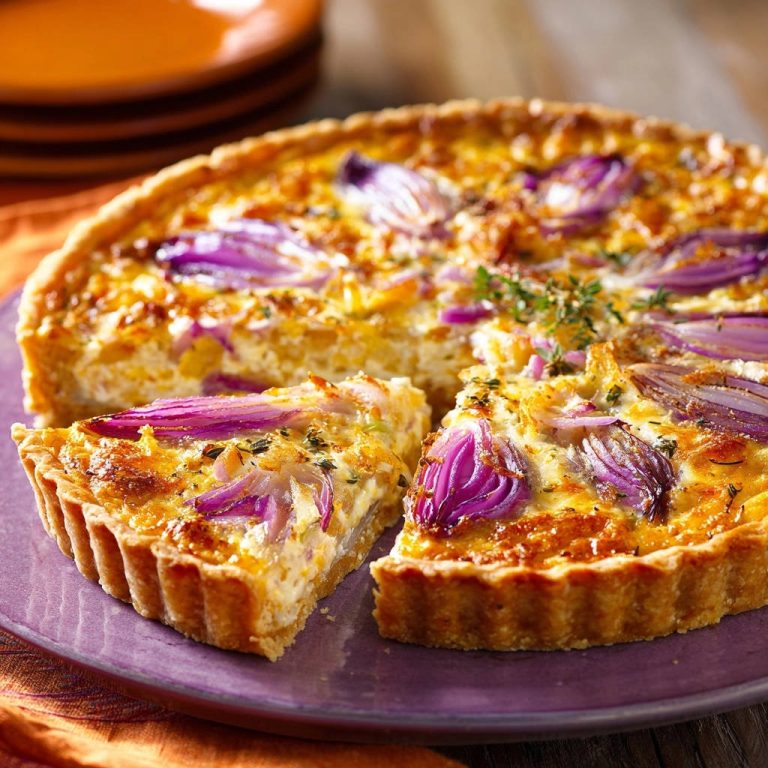 Cremige Zwiebel-Tarte angeschnitten auf einem Teller, mit sichtbaren roten Zwiebeln und Kräutern gefüllt.
