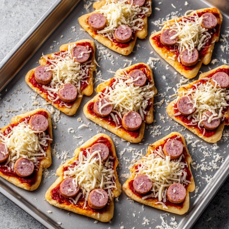 Festliche Pizzabäumchen mit Wurst und Käse roh auf einem Backblech vorbereitet.