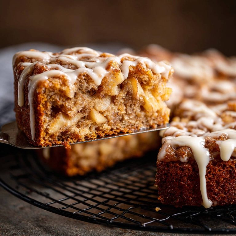 Saftiger Apfelkuchen mit Streuseln und Zimt, angeschnitten und mit Zuckerguss glasiert, gezeigt im Detail.