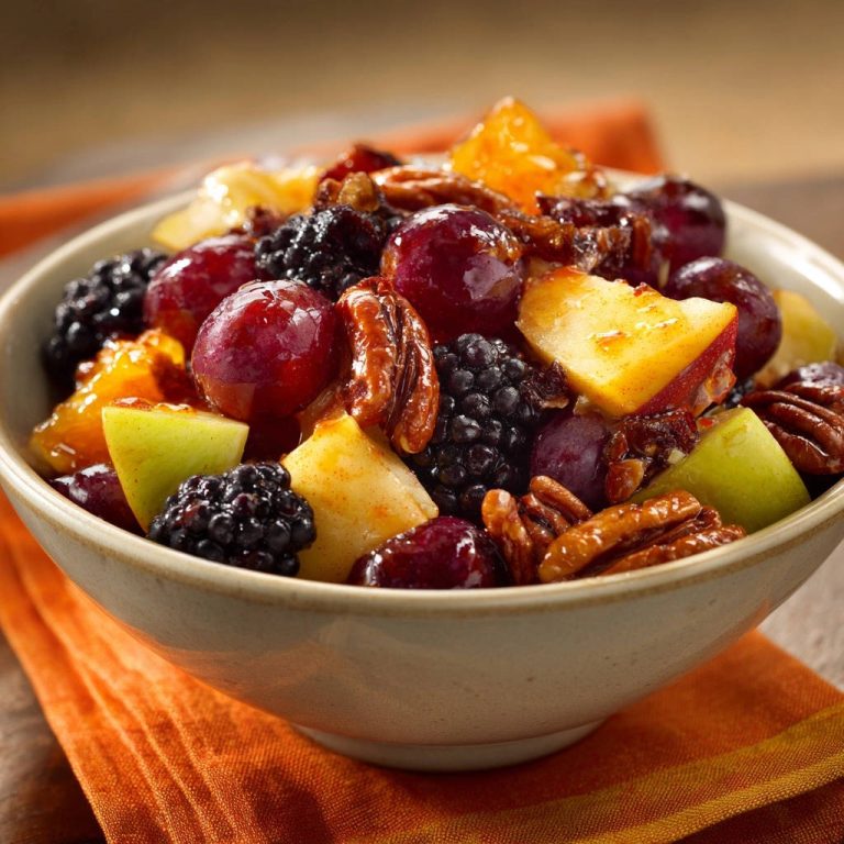 Glanzvoller Früchtezauber ist eine farbenfrohe Fruchtschüssel mit Beeren, Trauben, Äpfeln und Nüssen, Nahaufnahme.