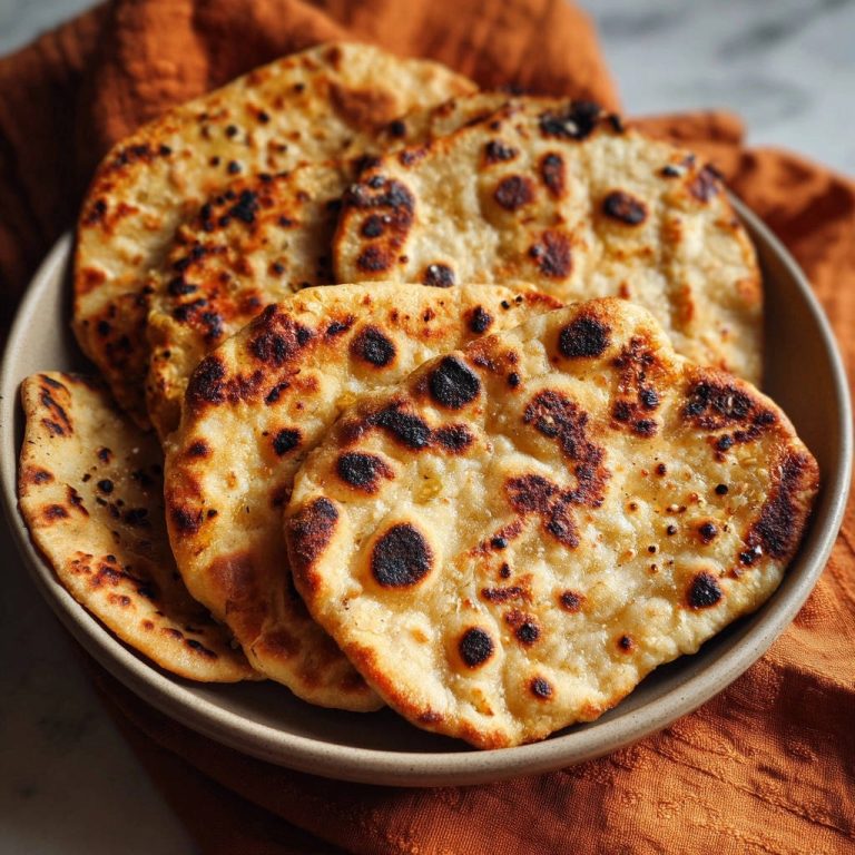Naan Brot mit einer detaillierten Aufnahme der gebackenen Textur und leicht verbrannten Stellen.