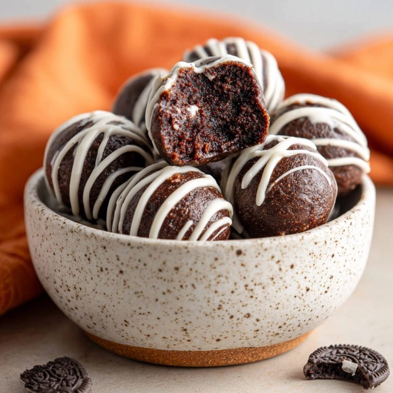 Schoko-Cookie-Kugeln als angeschnittene Kugel mit sichtbarer saftiger Schokoladenmasse und weißem Zuckerguss-Muster.