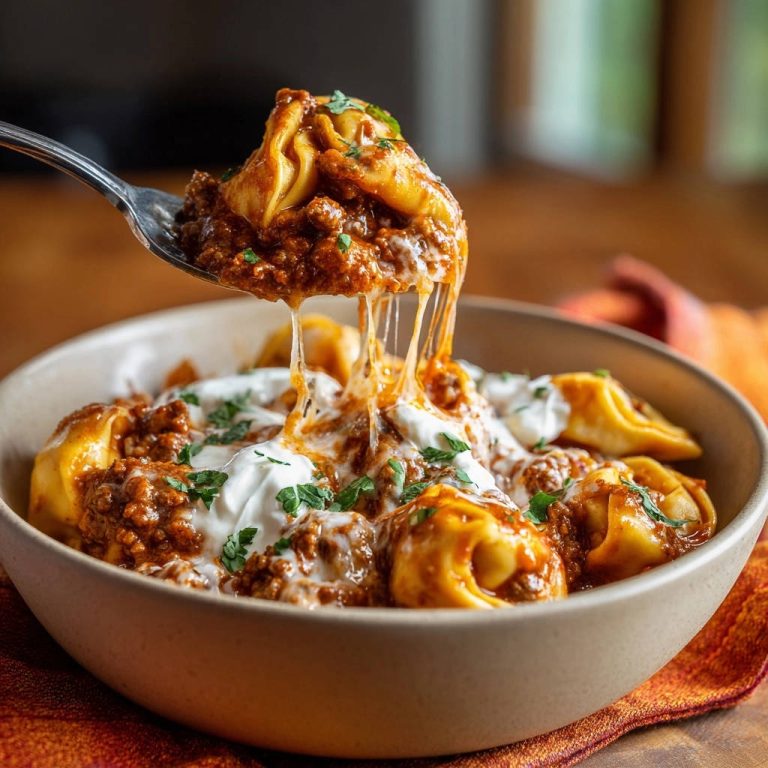 Blitz-Tortellini mit Hackfleischsauce: Ein Löffel mit geschmolzenem Käse und Tortellini wird aus der Schüssel gehoben.