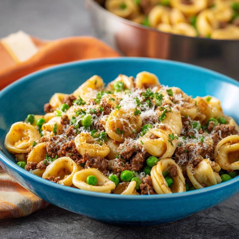 Herzhafte Orecchiette mit Hack und Erbsen, eine Nahaufnahme einer blauen Schüssel, garniert mit Parmesan und Petersilie.