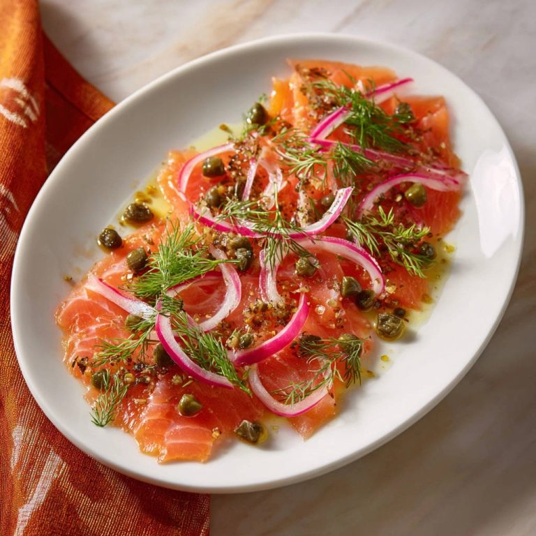 Zarter Lachs mit Kapern und Dill, elegant garniert mit roten Zwiebeln und frischem Dill auf einem weißen Teller.