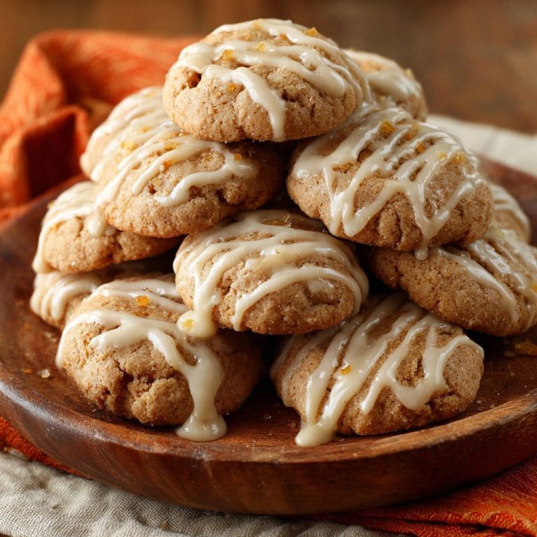 Würzig-weiche Orangen-Ingwer-Kekse mit detaillierter Zuckerguss-Glasur und Orangeat-Stückchen, auf einem Holzteller gestapelt.