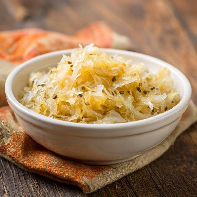 Zartes Sauerkraut nach Omas Art in einer weißen Schüssel, nah aufgenommen mit Kümmelsamen.