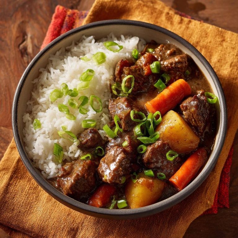 Asiatisches Rindfleisch-Curry mit Reis, garniert mit Frühlingszwiebeln, Karotten und Kartoffeln in einer Schüssel.