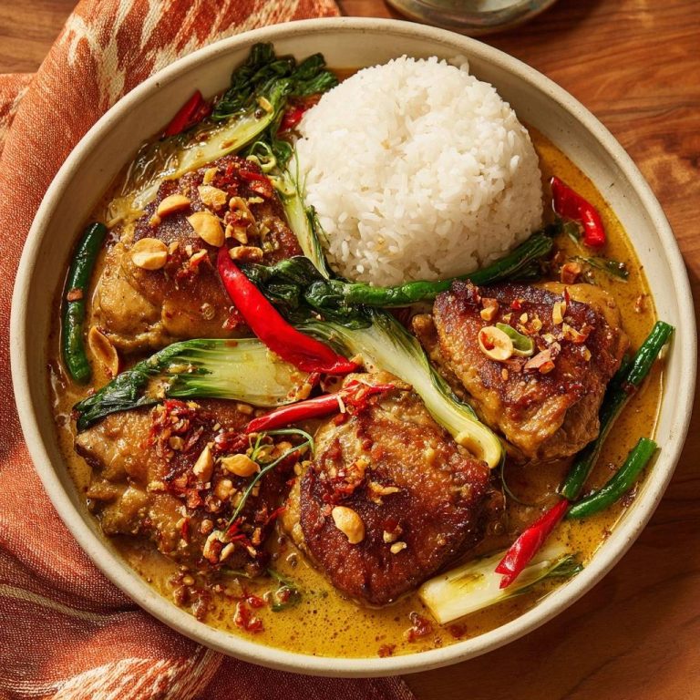 Thailändisches Hähnchen-Curry mit Erdnüssen und Pak Choi, nahaufnahme mit Reis und feurigen Chilis in einer Schüssel.