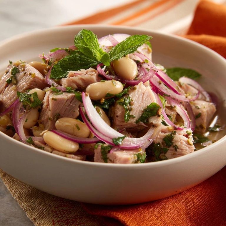 Weißbohnensalat mit Lammfleisch, Minze und roten Zwiebeln als Nahaufnahme in einer Schüssel.