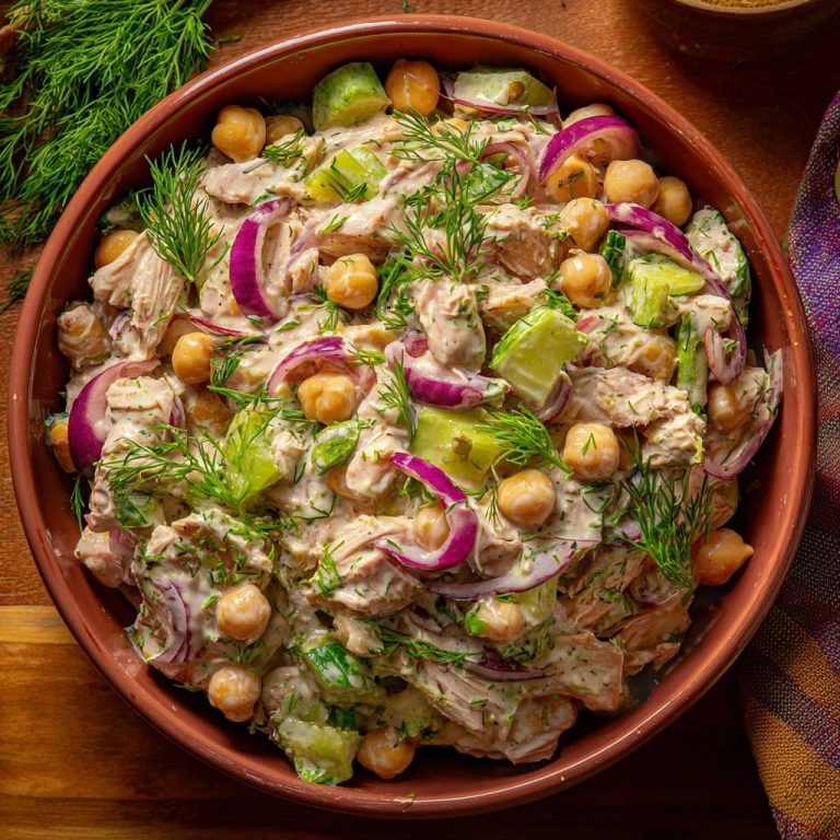 Cremiger Hähnchen-Gurken-Salat mit Kichererbsen, von oben in einer Schüssel serviert, mit Dill garniert.