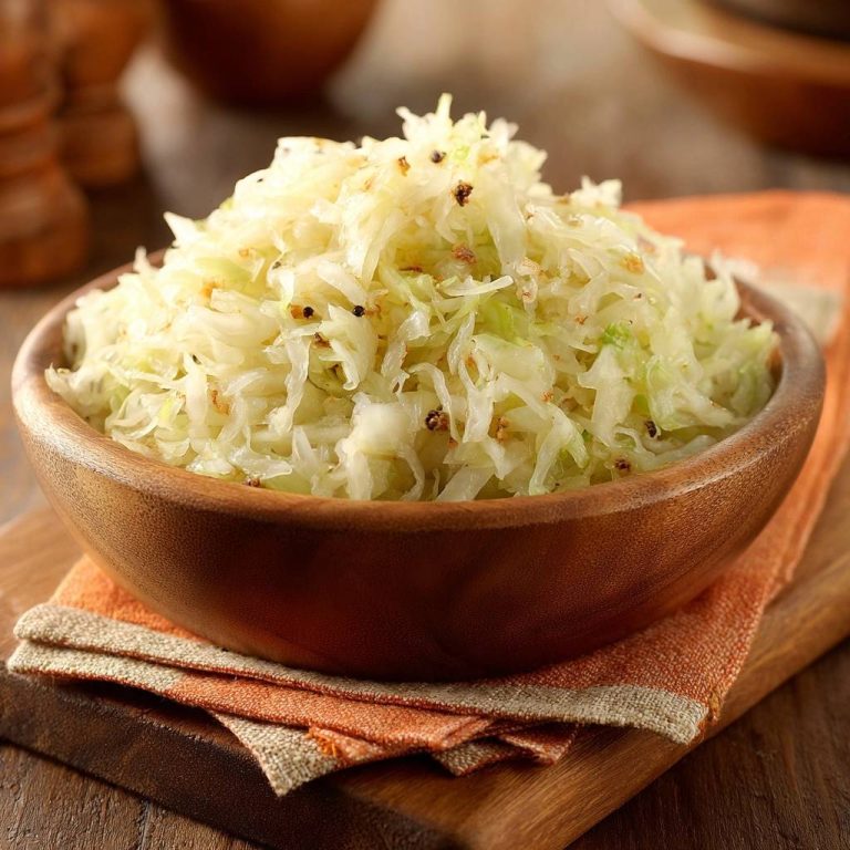 Knackiger Pfannkohl mit Pfeffer in einer hölzernen Schüssel, Nahaufnahme der Textur und des gehackten Kohls.