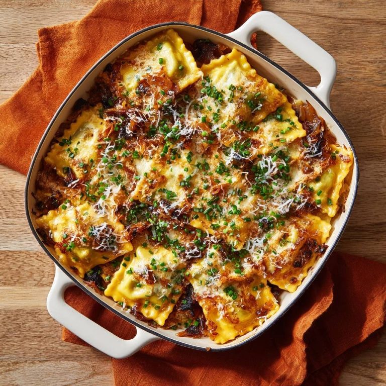 Knusprige Ofen-Ravioli mit Karamellzwiebeln, im Auflauf serviert und mit Kräutern garniert, von oben gesehen.