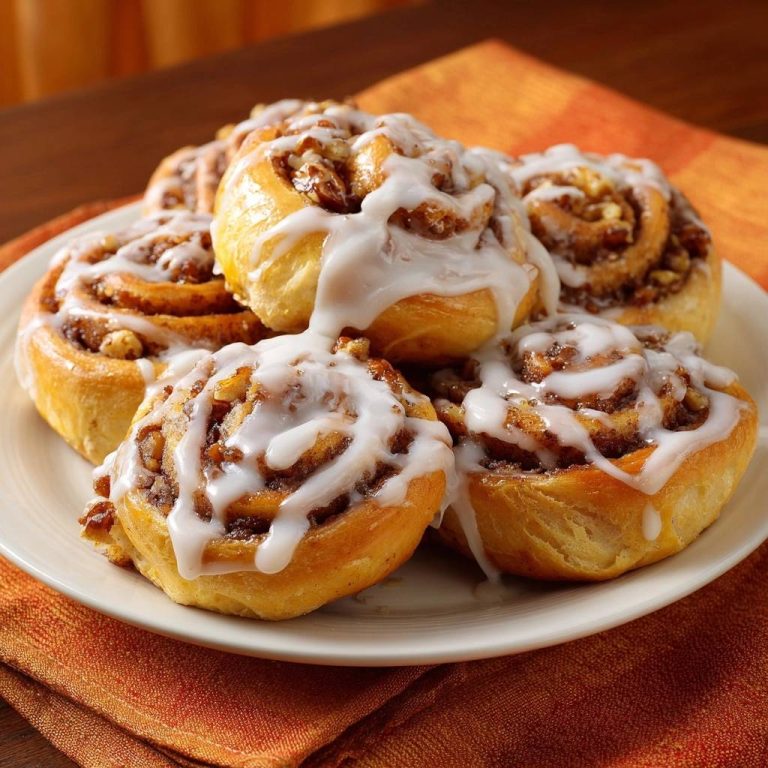 Zimtschnecken mit Pekannüssen, Nahaufnahme der fluffigen Brötchen mit reichlich weißer Glasur und Pekannüssen.