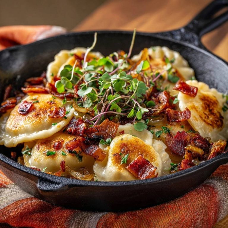 Knusprige Pfannen-Pierogi mit Speck und Zwiebeln, garniert mit frischen Microgreens in einer Gusseisenpfanne.