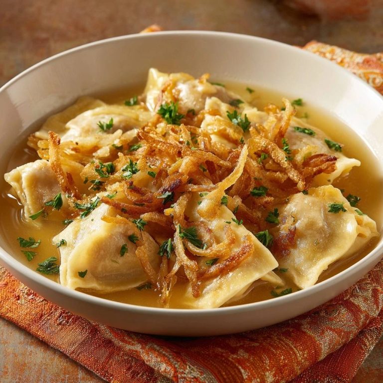 Maultaschen in goldener Brühe mit knusprigen Zwiebeln und frischen Kräutern, serviert in einer weißen Schüssel.