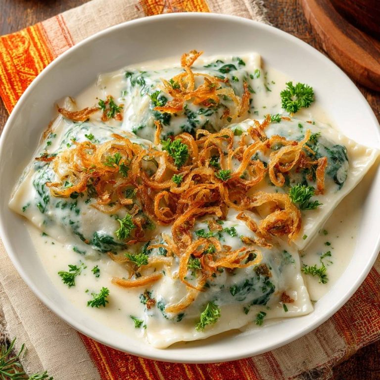 Spinatravioli in cremiger Soße mit knusprigen Zwiebeln und Petersilie garniert, Nahaufnahme der cremigen Sauce
