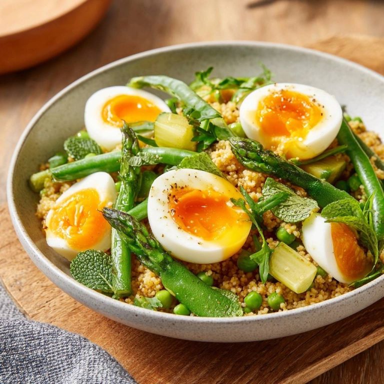 Frühlings-Couscous mit grünem Spargel und Ei, serviert in einer Schüssel, mit einem weichgekochten Ei im Anschnitt.