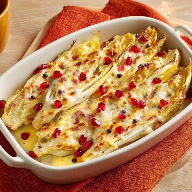 Gebackener Endivie-Gratin mit Käse und Granatapfel, im Detail mit geschmolzenem Käse und roten Granatapfelkernen garniert.