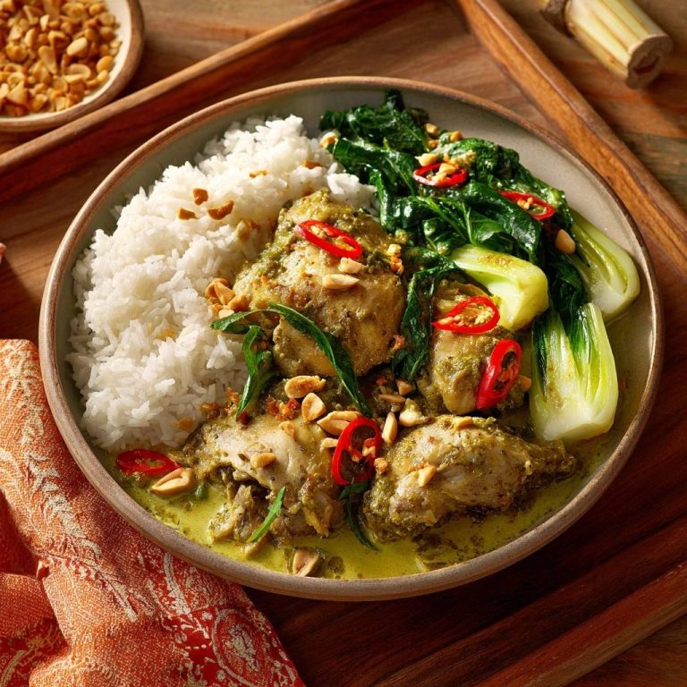 Cremiges grünes Thai-Curry mit Hähnchen, serviert mit Reis und garniert mit Chilis und Erdnüssen.