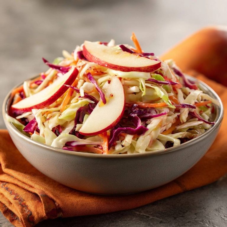 Knackiger Apfel-Krautsalat in einer Schüssel, garniert mit Apfelscheiben und Rotkohlstreifen.