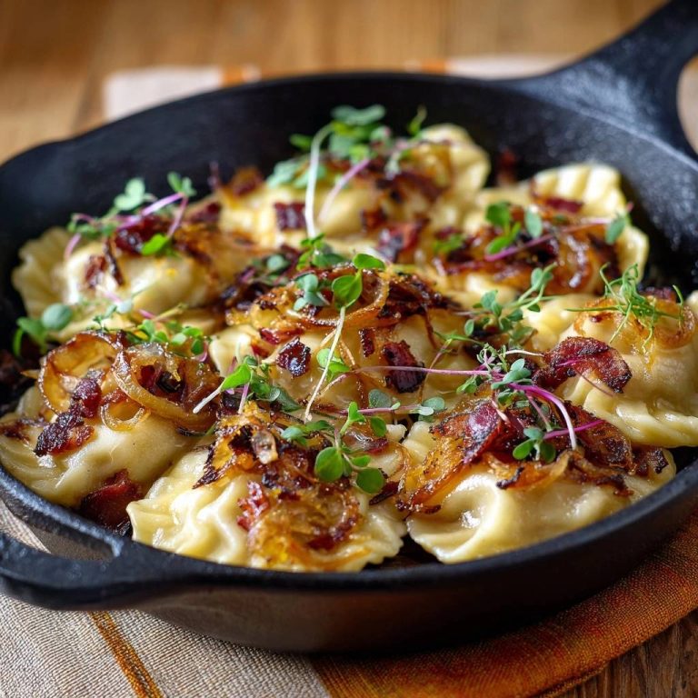 Knusprige Pierogi mit geräucherten Pilzen und karamellisierten Zwiebeln, garniert mit frischen Kräutern in einer Gusseisenpfanne