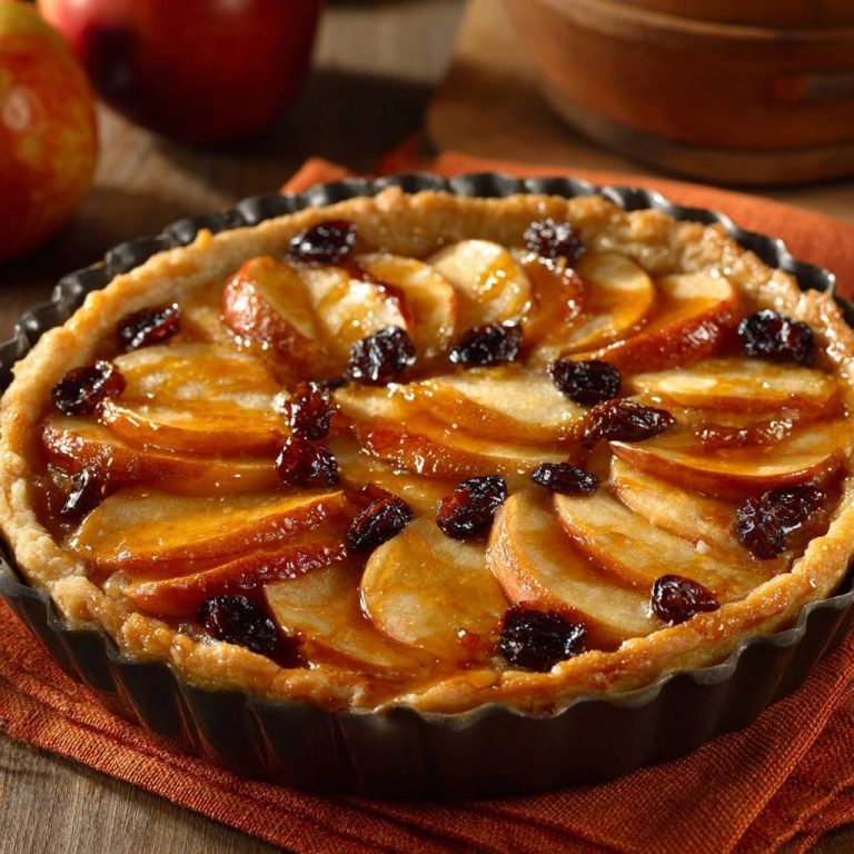 Klassische Apfel-Tarte mit Rosinen und glasierten Äpfeln, Nahaufnahme des gebackenen Kuchens in einer Tartform.